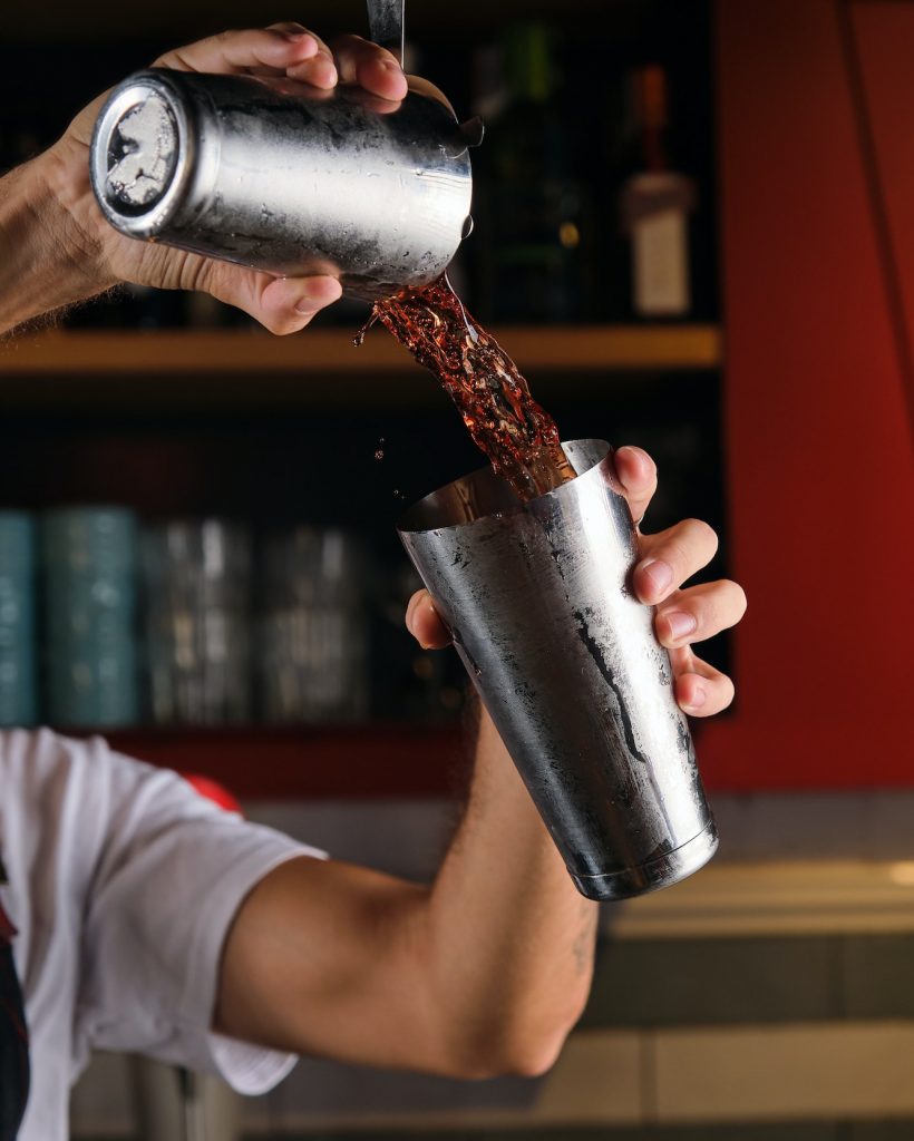 Unrecognizable barman mixing drink in pub